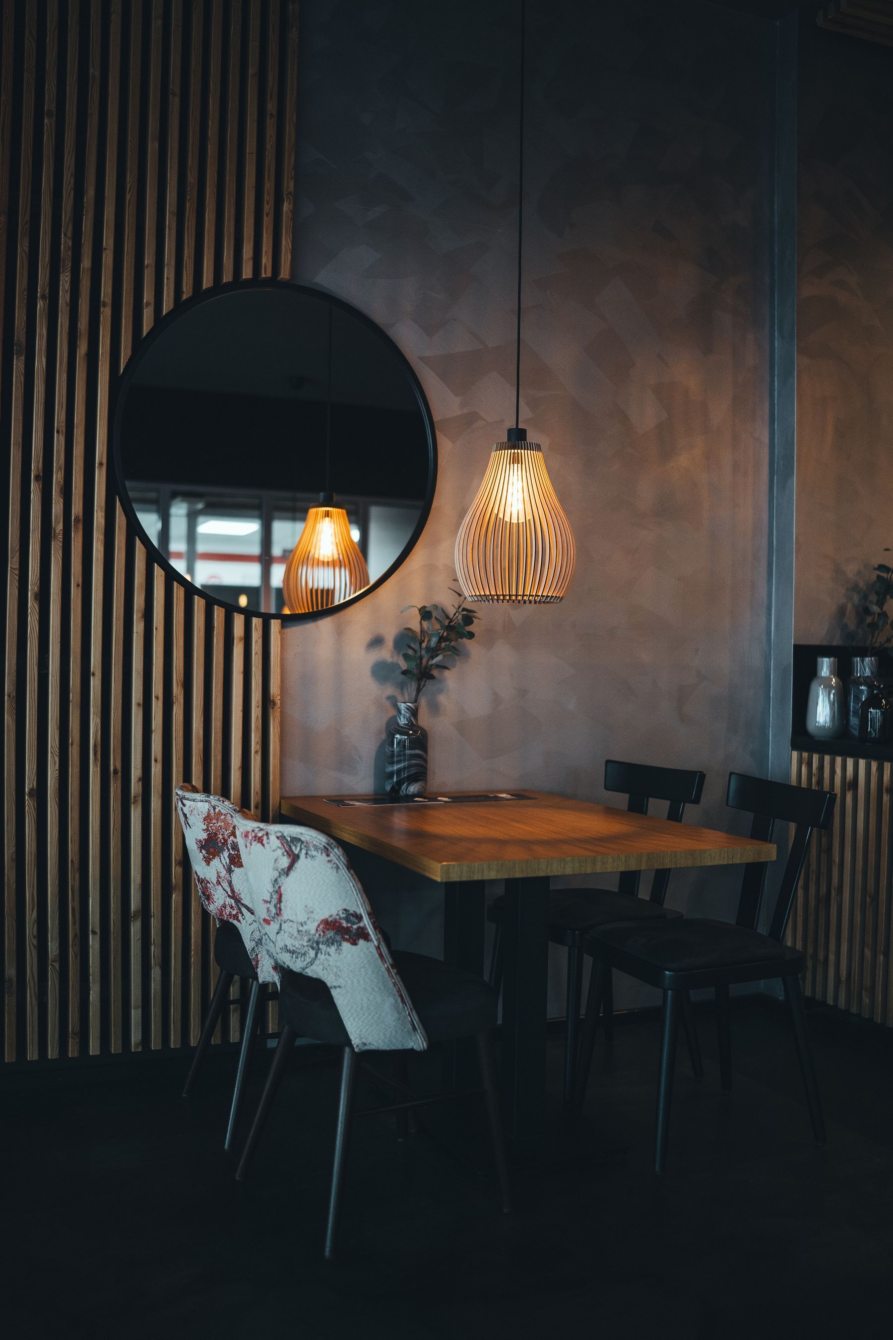 Detalle de la sala con espejo redondo y listones de madera