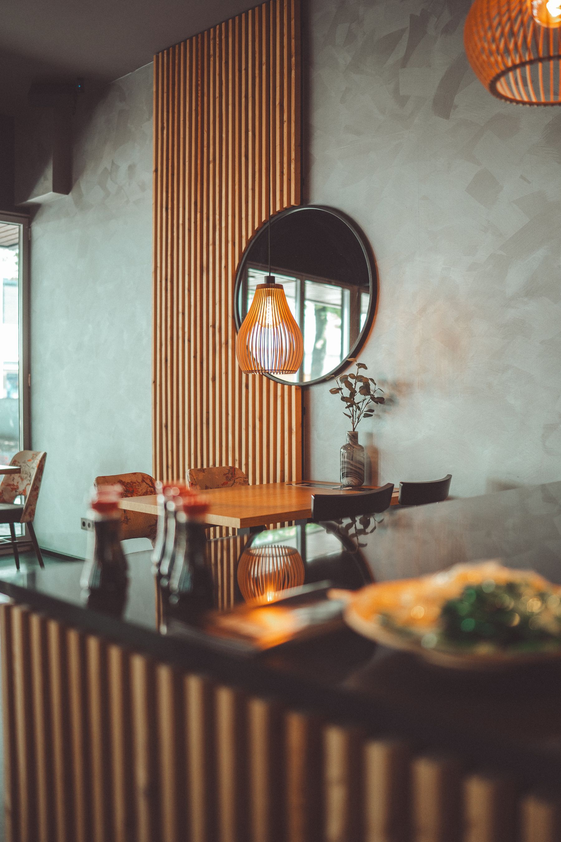 Rincón del comedor de Mr. Chen con mesa de madera, espejo redondo y lámpara colgante