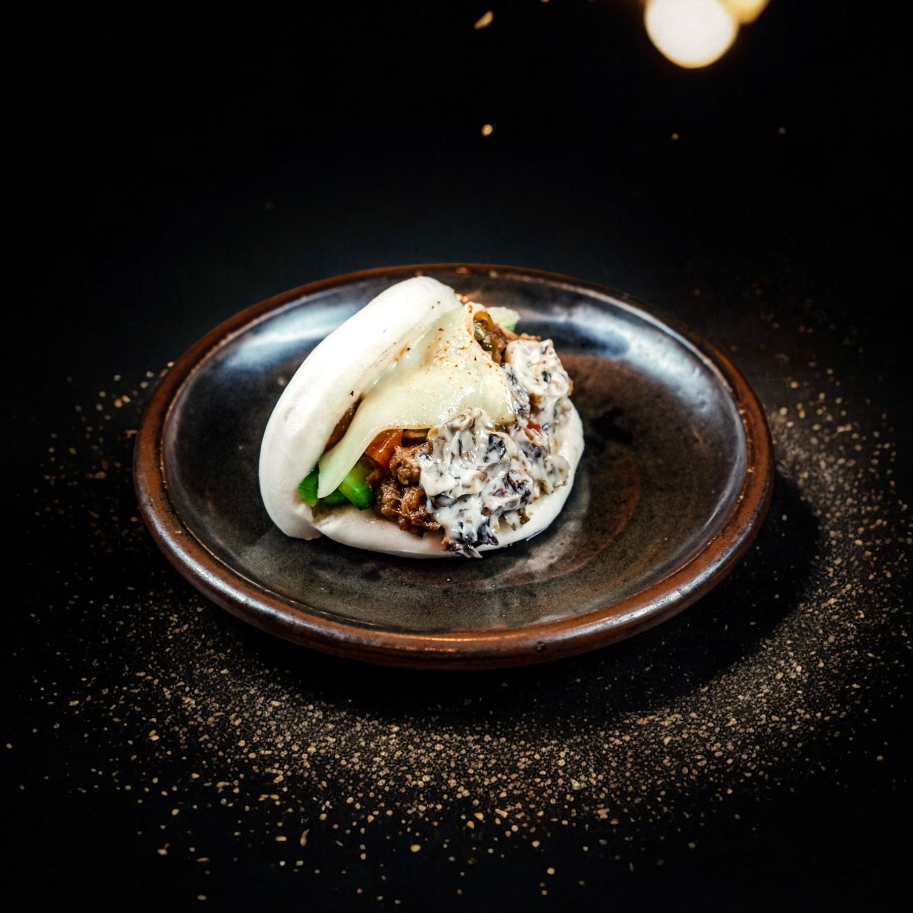 Bao relleno de pollo crujiente servido en un plato oscuro